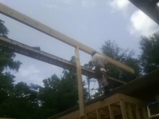 Carpenter setting a ridge beam over a new addition frame — Ice Dam Removal by Roofing Brothers in Welch