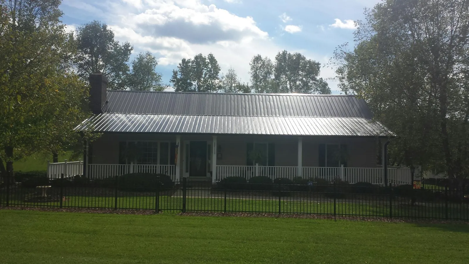 Gray metal roof on a brick ranch with a full width front porch — Gutter Guard Installation work by our crew in Welch